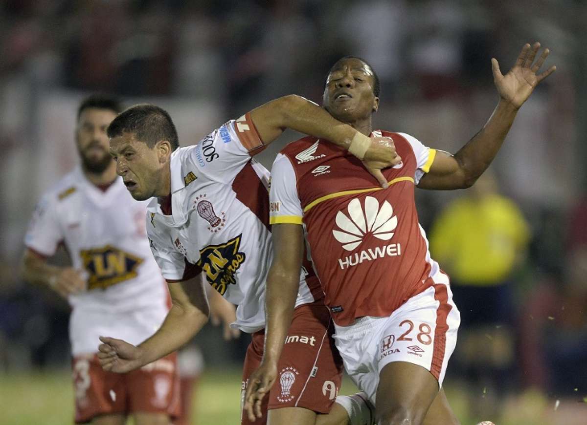 El delantero ecuatoriano Daniel Angulo (der.), del Santa Fe, intenta liberarse de la marca del defensa de Hurac&aacute;n Hugo Nervo. Foto: AFP