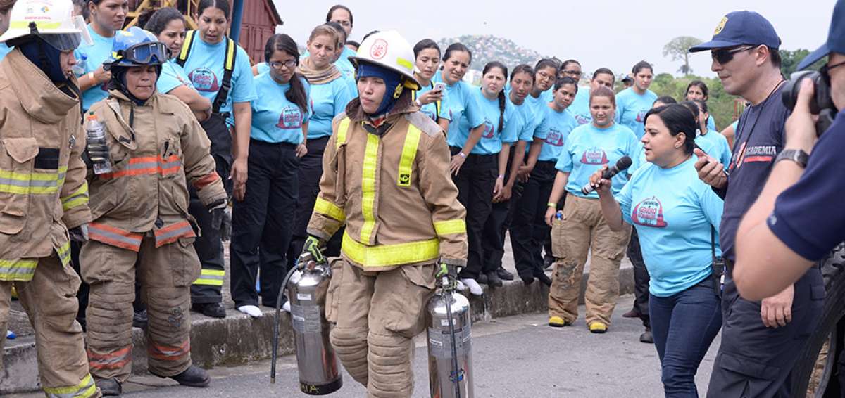 Una de las pruebas que realizaron las participantes fue cargar  pesados extintores usando el traje de protecci&oacute;n de los bomberos.