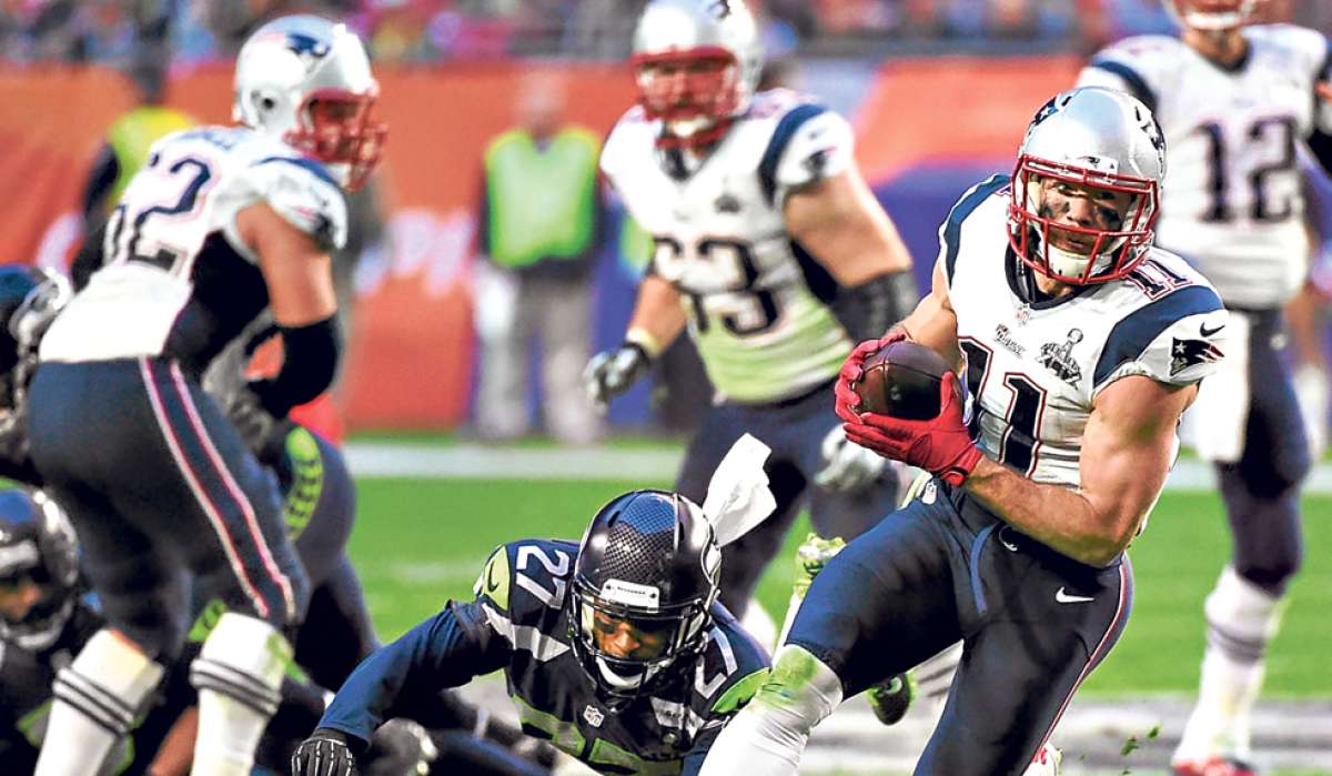 Julian Edelman (d), de los Patriotas de Nueva Inglaterra, lleva la pelota en uno de los &uacute;ltimos ataques del Super Bowl que ganaron anoche a los Seattles. Foto: AFP