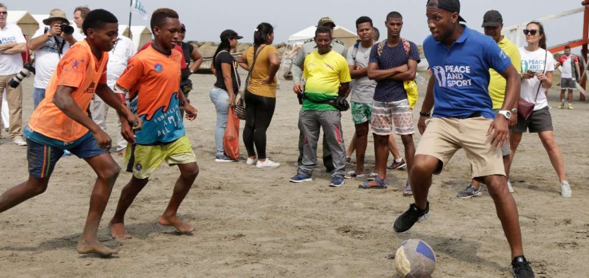 El futbolista marfile&ntilde;o Didier&nbsp;Drogba&nbsp;(i) conduce una pr&aacute;ctica de f&uacute;tbol con un grupo de j&oacute;venes de las fundaciones Amigos del Mar y F&uacute;tbol con Coraz&oacute;n este domingo en Cartagena.