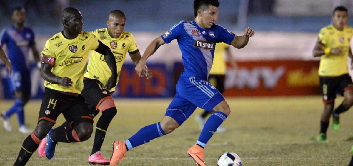 El mediocampista Fernando Gaibor (c), de Emelec, controla el bal&oacute;n y se despega de la marca del volante de marca amarillo Segundo Castillo (i); atr&aacute;s observa la acci&oacute;n otro jugador de Barcelona, Ely Esterilla.