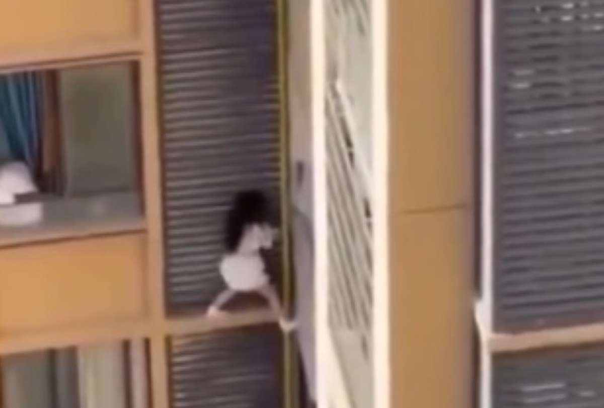Video viral: mujer huye por la cornisa de un edificio y se salva de caer