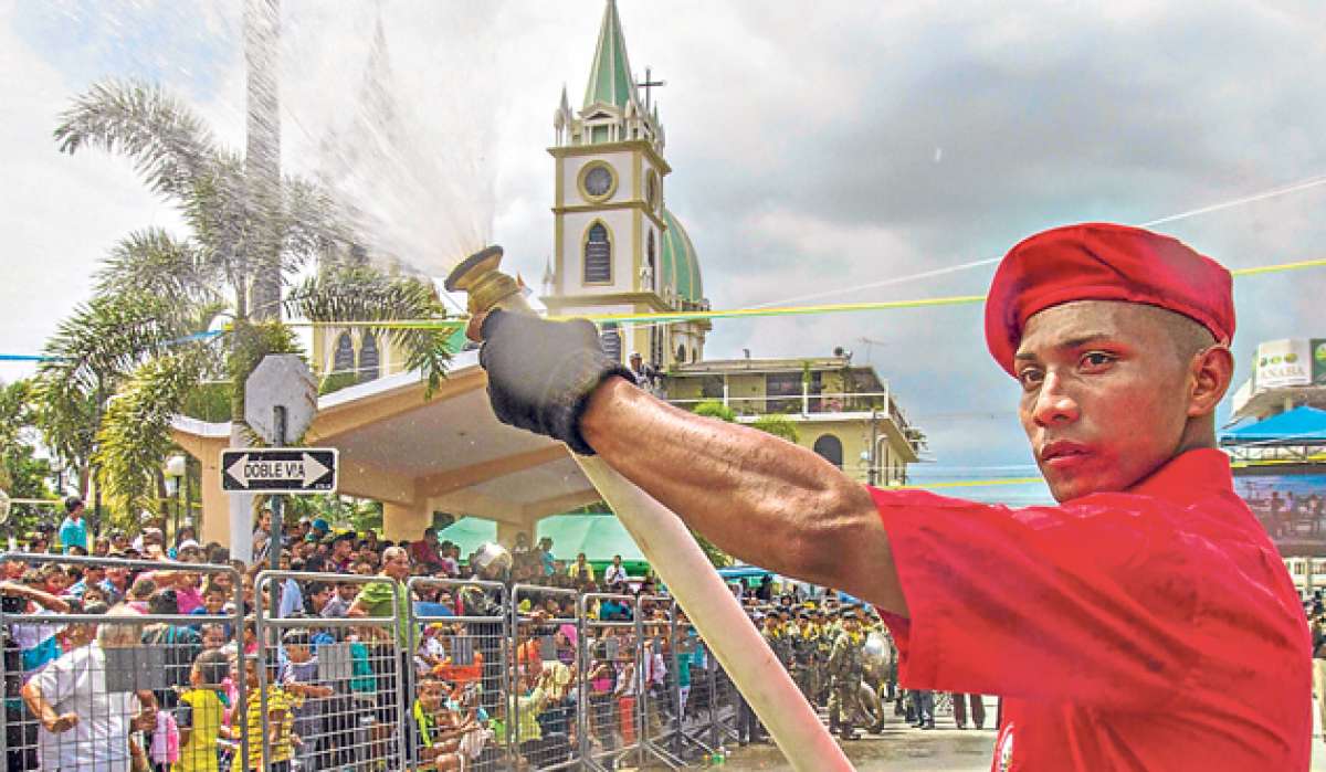 Un bombero moja a la multitud que acudi&oacute; a ver el desfile para apaciguar el intenso sol que soport&oacute; ayer Yaguachi. Foto: Cortes&iacute;a / Vicepresidencia