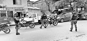 Los polic&iacute;as nacionales, ataviados con mascarillas, cumplen con el control durante el toque de queda en la ciudad de Esmeraldas.