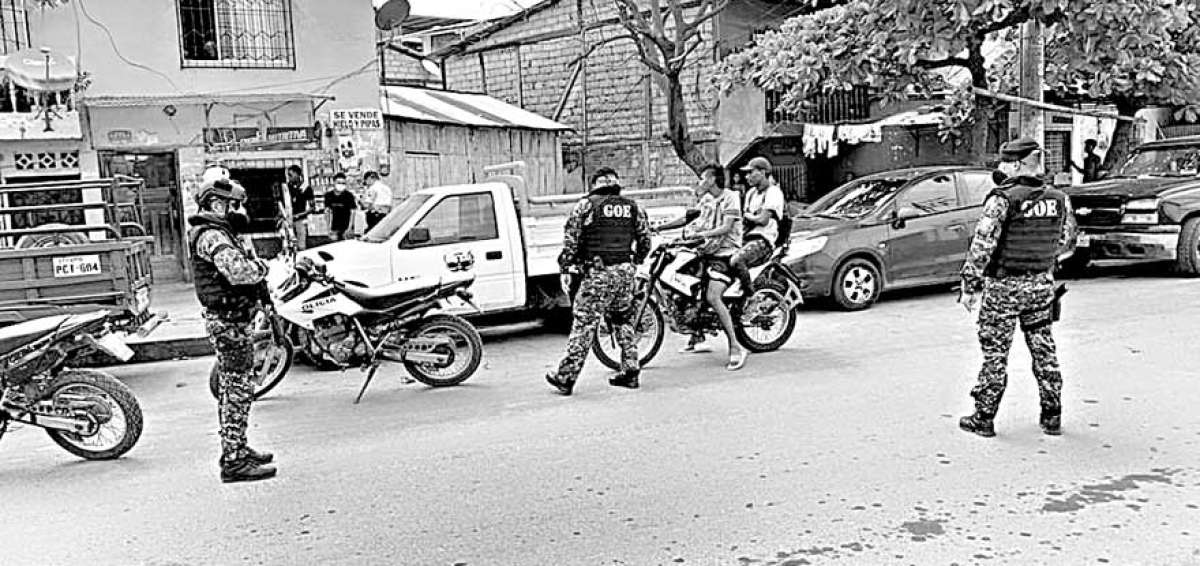 Los polic&iacute;as nacionales, ataviados con mascarillas, cumplen con el control durante el toque de queda en la ciudad de Esmeraldas.