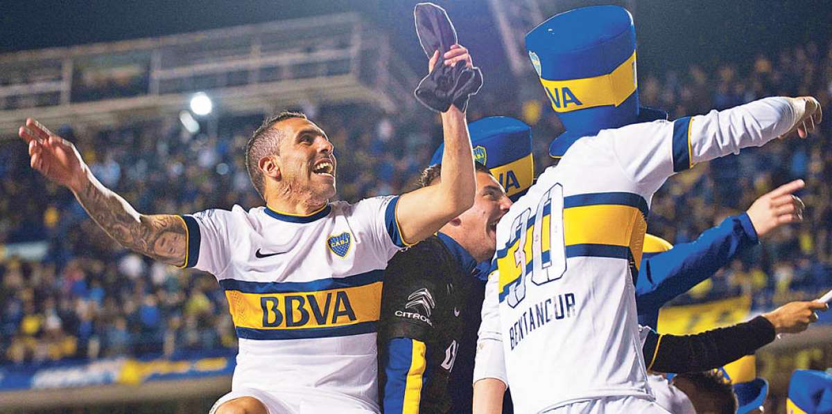 Carlos T&eacute;vez (izq.), subido en uno de los arcos, canta junto a sus compa&ntilde;eros e hinchas del equipo. Foto: AFP