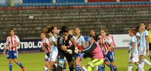 La arquera de Argentina y una jugadora de Paraguay pelean durante un partido.