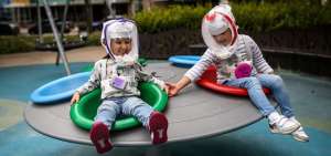 Ni&ntilde;os juegan e interact&uacute;an mientras usan un casco similar al de astronautas, para evitar el contagio de Covid-19 en Bogot&aacute;, Colombia.