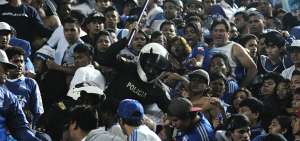 Un miembro de la Polic&iacute;a Nacional intenta separar a supuestos hinchas de Emelec, la noche del lunes, en una de las generales del estadio George Capwell.