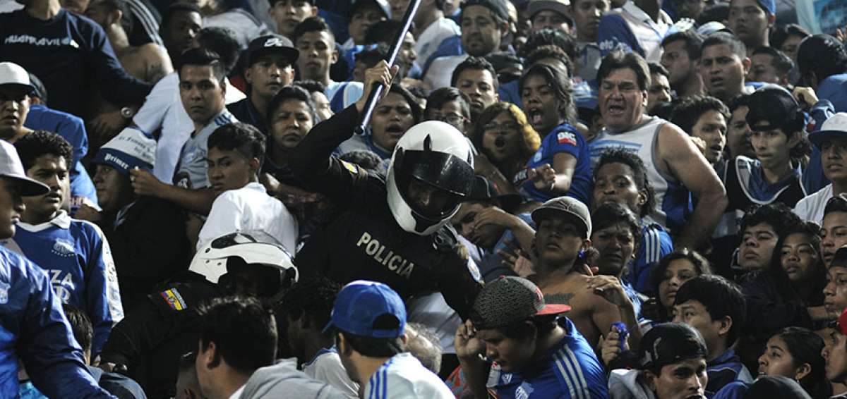 Un miembro de la Polic&iacute;a Nacional intenta separar a supuestos hinchas de Emelec, la noche del lunes, en una de las generales del estadio George Capwell.