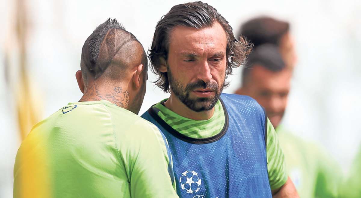 El mediocampista Andrea Pirlo (der.) conversa con el chileno Arturo Vidal durante un entrenamiento previo a la final de la Champions League. Foto: AFP