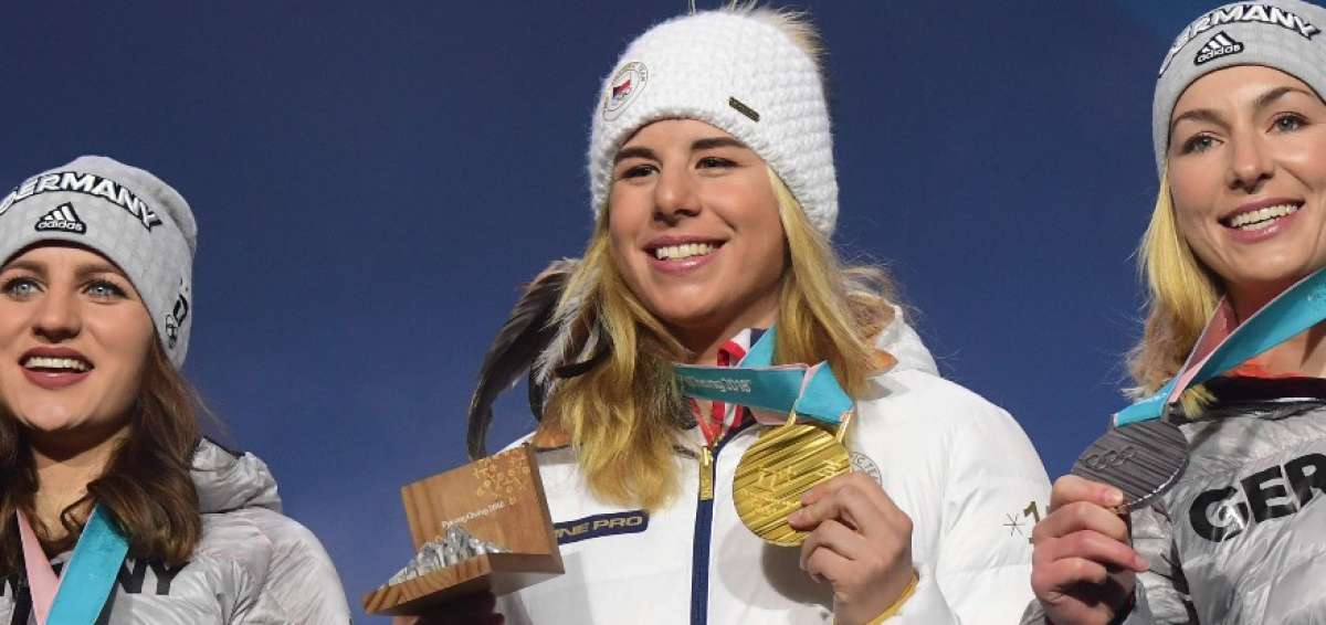 La checa Ester Ledecka (centro) muestra su medalla de oro lograda en el supergigante de esqu&iacute; alpino.