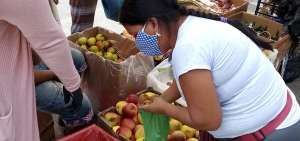 &rarr;Una mujer compra frutas a una vendedora. Ambas llevan mascarillas para protegerse del virus del covid-19.   