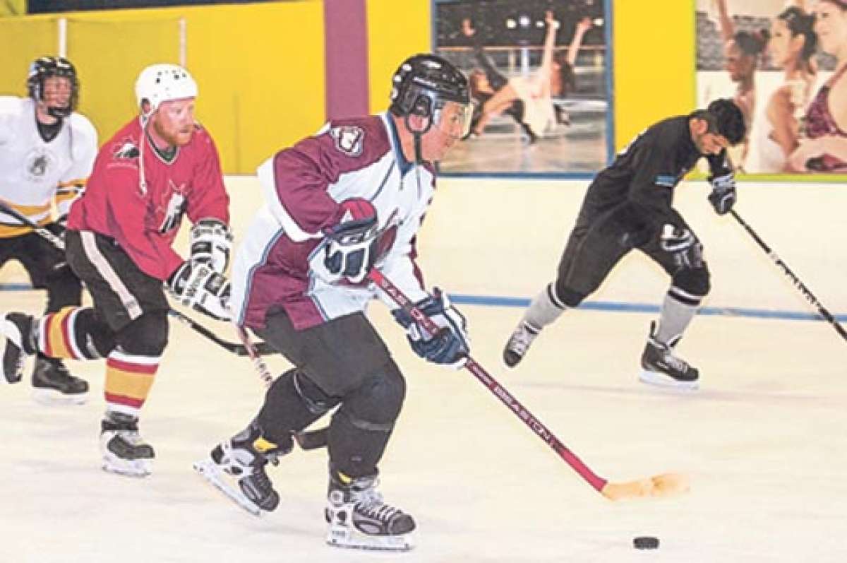 Jugadores de los Quito Cocks y Black Dragons entrenan en el Palacio del Hielo. Juan Carlos Casares (centro), del Quito Cocks, domina el pack (disco) ante la marca del canadiense Cameron Smith (de rojo). FOTO: JOHN GUEVARA.