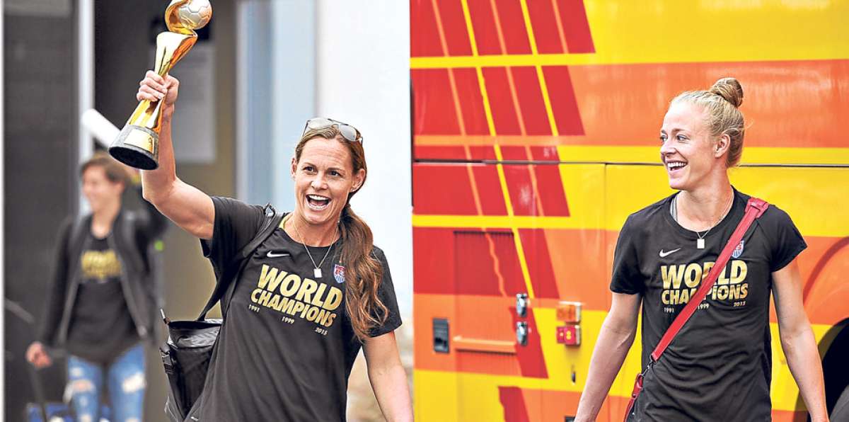 Christie Rampone (izq.) muestra el trofeo a su llegada a Los &Aacute;ngeles. La acompa&ntilde;a Becky Sauerbrunn. Foto: AFP