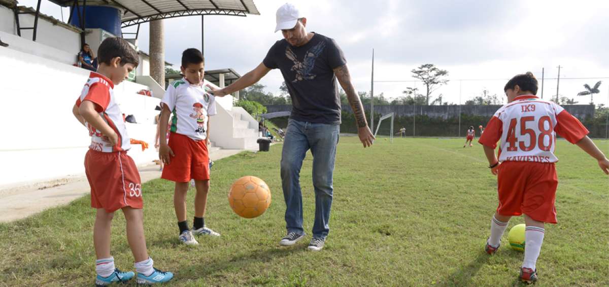 Jaime Iv&aacute;n Kaviedes hace cascaritas mientras tres alumnos de su escuela de f&uacute;tbol lo observan con admiraci&oacute;n.