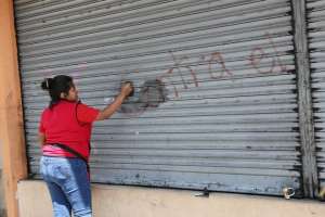Integrantes del FUT realizan la limpieza de grafitos en puertas plegables y paredes del centro de Quito. Foto: Cortes&iacute;a